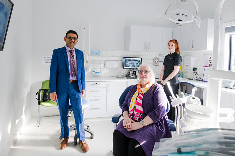 dentist with patient and dental assistant in surgery room